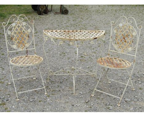 A weathered contemporary cream painted folding demi-lune garden table with lattice top and trailing foliate detail, 80 cm wid