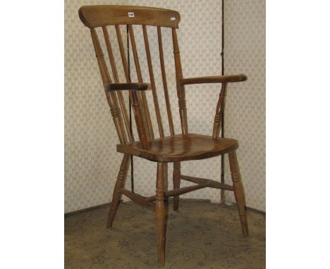 A Windsor stained elm and beechwood stick back open armchair with saddle shaped seat, raised on turned supports and stretcher