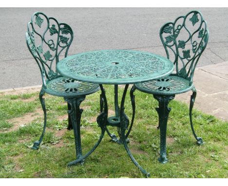 A green painted cast aluminium garden terrace table of circular form with decorative pierced top raised on swept supports tog