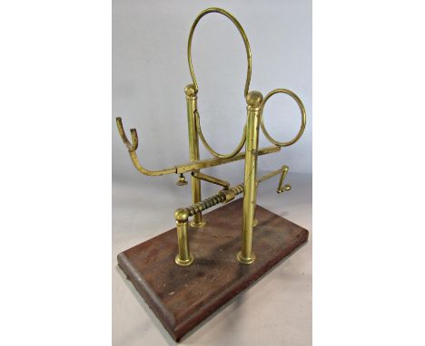 A vintage mechanical brass wine cradle, raised on a wooden base. 