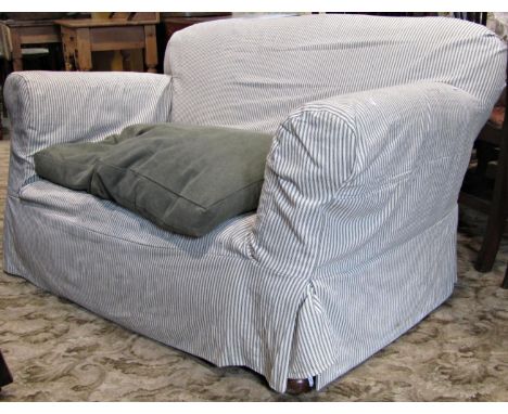 A Edwardian two seat sofa, with rolled arms, upholstered finish and later loose alternating stripped covers, set on turned bu