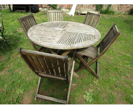 A weathered hardwood circular topped garden table with slatted panels raised on x framed folding supports, 126 cm diameter, t