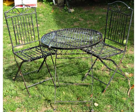 A weathered contemporary three piece folding ironwork garden terrace set with decorative pierced lattice loop and scroll deta