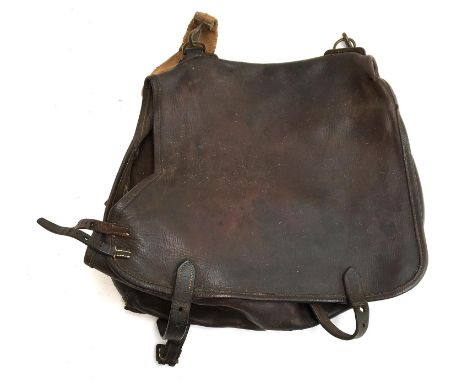 A vintage leather hunting satchel with canvas shoulder strap for transporting a terrier 