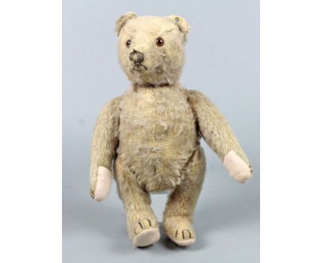 Steiff Teddybär 1950er Jahre mit dem Knopf im Ohr und Reste der gelben Leinenfahne, hellbeiges Fell, der Teddy ist über Schei