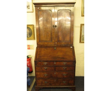 A Georgian walnut bureau bookcase, the top with twin fielded doors revealing a fitted interior, the base with fall flap fitte