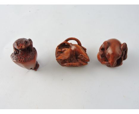 A carved hardwood netsuke, in the form of rat curled in a ball; together with two further carved hardwood netsuke. (3)
