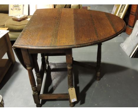 An oak gate leg dining table with rounded rectangular tin flap top on turned under frame. 88cm.