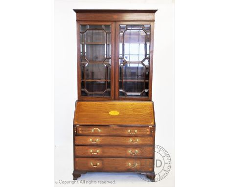 An Edwardian inlaid mahogany Sheraton revival bureau bookcase, having a moulded cornice above an inlaid and cross banded frie