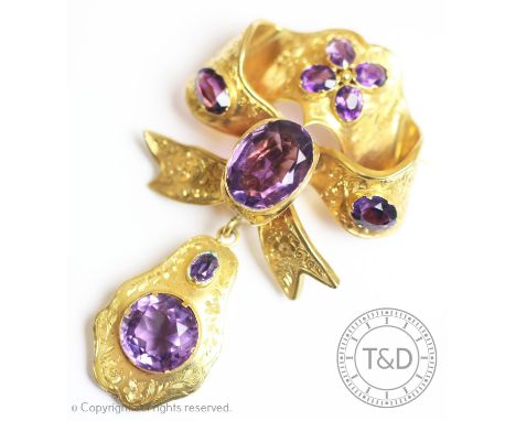 A Victorian amethyst set brooch, of ribbon form and drop with engraved floral pattern, claw set with nine mixed cut amethysts