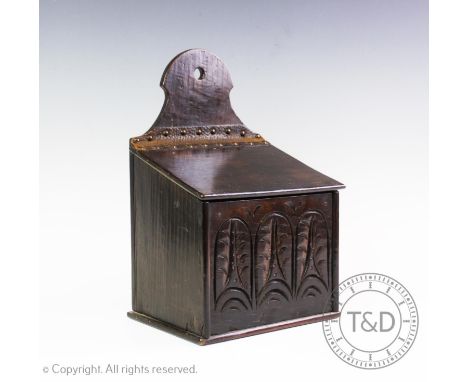 A 19th century carved oak candle box, the rectangular cover hinged by a leather strap above a front panel carved with stylise