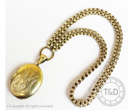 A Victorian gilt metal locket pendant, oval form with engraved monogram and pattern to exterior, attached yellow metal fancy 
