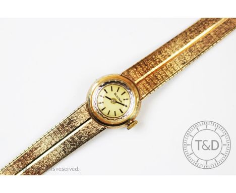 A lady's Bulova 9ct gold wristwatch, London 1965, the gilt face with black batons and textured bezel, case size 18mm, attache