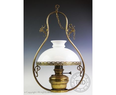 A Victorian brass hanging oil lamp, the brass frame of swelling form enclosing the brass lamp with reservoir, opaque glass sh
