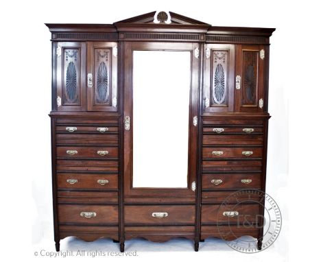 An Edwardian walnut compactum wardrobe in the aesthetic style, by Lamb of Manchester, having an architectural pediment above 