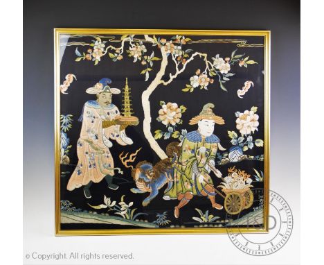 A late 19th century Chinese silk work panel, depicting a figure presenting an ivory pagoda, a dog of fo and a man supporting 