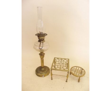 A Victorian brass oil lamp with cut glass reservoir and two brass trivets