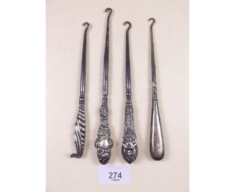 Three silver button hooks and a white metal one
