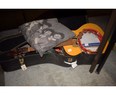 An acoustic guitar; tambourine; harmonica; sheet music; and a Beatles cushion.