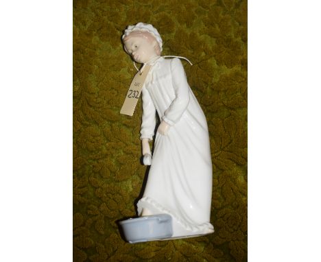 A Nao figure of a young girl wearing a nightdress preparing for bed.