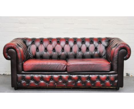 Buttoned red leather Chesterfield settee, length 180cms, two wing-backed easy chairs and a stool, (4).