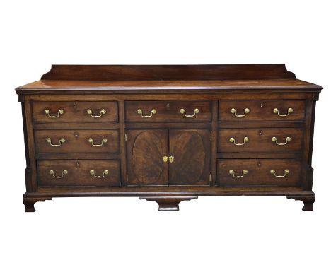 An impressive George III mahogany dresser base Having a rectangular moulded and crossbanded top above an arrangement of seven