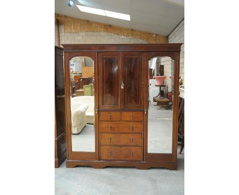 An Edwardian inlaid mahogany wardrobeHaving an inlaid and cross banded molded cornice above a central beveled mirrored door f