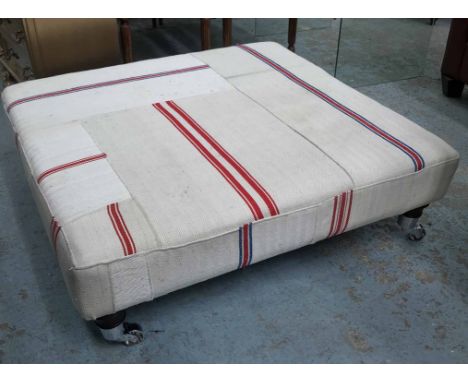 HEARTH STOOL, upholstered in vintage grain sacks, raised on turned supports and castors, 98cm L x 94cm W x 32cm H. 