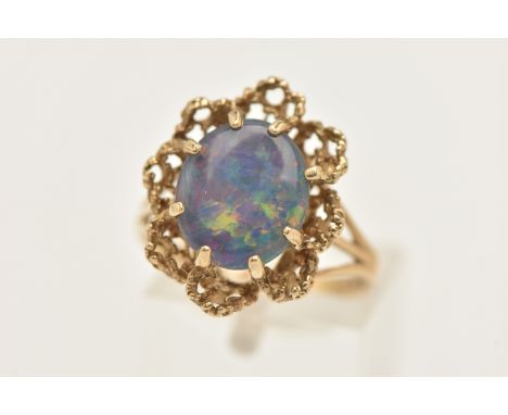 A 9CT GOLD OPAL TRIPLET RING, set with an oval cut opal triplet, in an eight claw setting to the textured open work scalloped