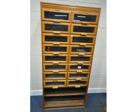 A 20TH CENTURY OAK HABERDASHERY CABINET, fitted with sixteen glass fronted drawers, above a shelf, width 92cm x depth 49cm x 