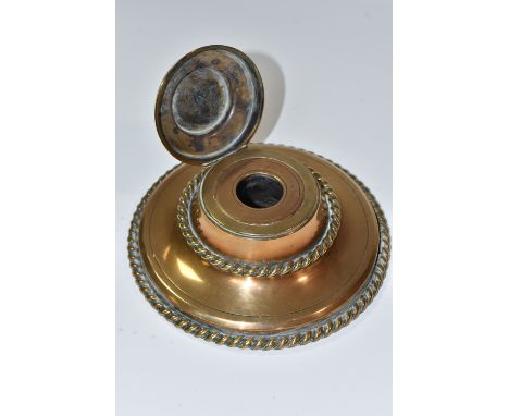 A NINETEENTH CENTURY BRASS INKWELL, of circular form with rope style edging, and a Pietra dura floral panel on the cover, wit