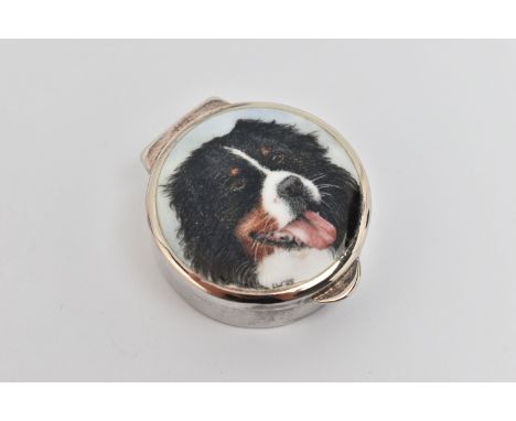A CIRCULAR SILVER ENAMEL PILL BOX, displaying a Burnese mountain dog to the hinged cover, black fabric interior, makers mark 