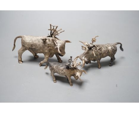 Three miniature white metal model cocktail stick holders? each modelled as a bull with sword shaped sticks, two stamped sterl