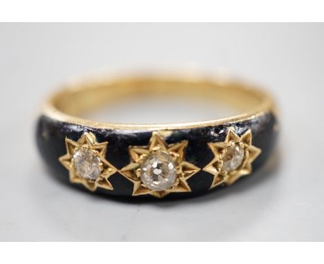 An Edwardian 18ct, black enamel and three stone gypsy set diamond mourning ring, size Q/R, gross weight 6.6. grams, the inter