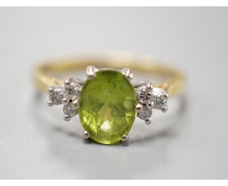 A modern 18ct gold and oval cut peridot ring, with diamond set shoulders, size M, gross weight 3 grams.