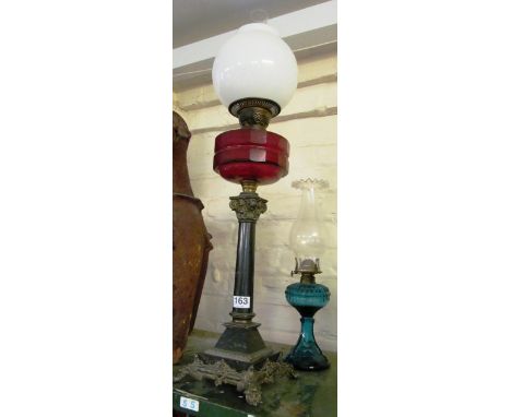 An oil lamp red reservoir and opaque shade and another oil lamp