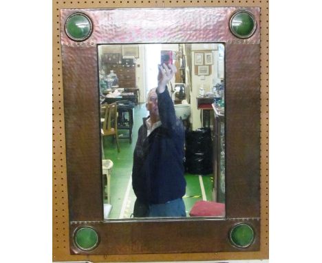 A Liberty copper mirror with green (ceramic?) circle decoration to each corner (slight dent bottom left) with label to revers