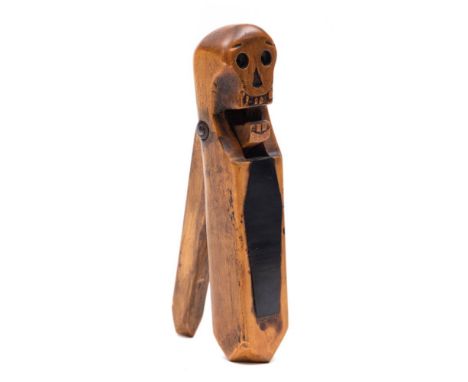 A 19th century treen nut cracker with carved skull decoration:,  the lower jaw hinged by a steel pin with ebony coffin inlaid