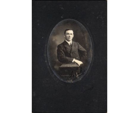 A black and white oval half-length studio portrait photograph of F E Davies: signed 'Frank' in blue ink lower right, in a car