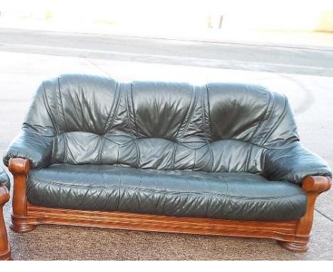 A wooden carved three seater sofa with green leather studded upholstery 97cm (h) x 195cm (w) x 82cm (d)