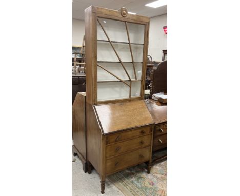 A 1930s oak bureau bookcase, the glazed bookcase top with starburst style decoration over a sloping fall enclosing a basic fi