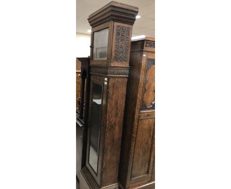 A circa 1900 carved oak long case clock case, the hood decorated with panels of acorns and foliage, etc., the trunk with oak 