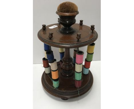 A Victorian mahogany six section bobbin stand with central circular pin cushion of thistle form, on a central turned column w