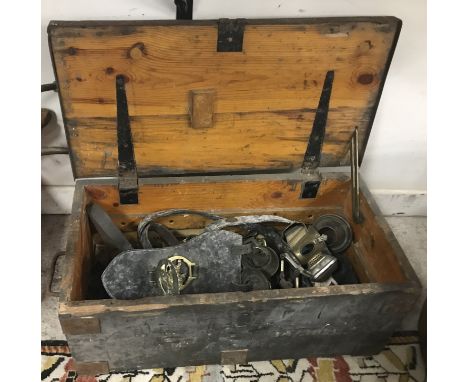 A wooden trunk containing various house brasses, martingales, Lucas cycle lamp, etc