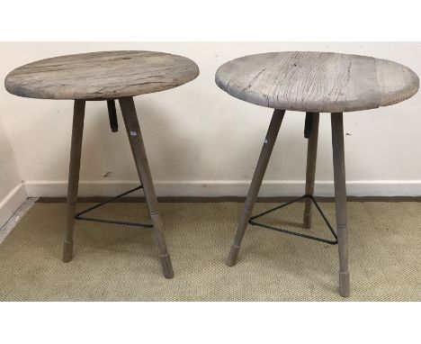 A pair of driftwood type circular sculpture style tables, the revolving tops on splayed tripod supports united by an iron str
