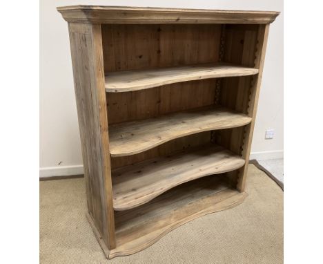 A pine open shelf unit, the serpentine shaped top with moulded edge over three adjustable shelves, raised on a shallow plinth