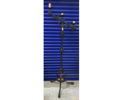 A patinated iron three light floor lamp in the Arts & Crafts taste with Gothic style candle type light holders and fleur de l