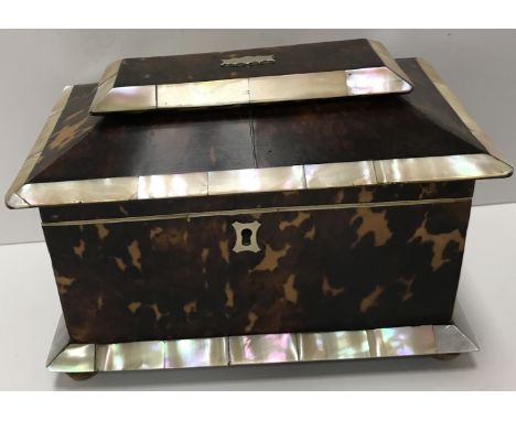 An early 19th Century tortoiseshell and mother of pearl banded tea caddy, the cover opening to reveal two lidded compartments