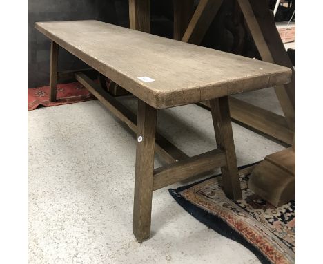 An oak bench in the Arts & Crafts style, the plank top on splayed end supports united by a centre stretcher, 148 cm x 34 cm x