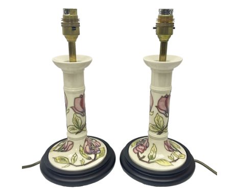 Pair of Moorcroft table lamps of candlestick form in magnolia pattern, with Moorcroft shades, H50cm